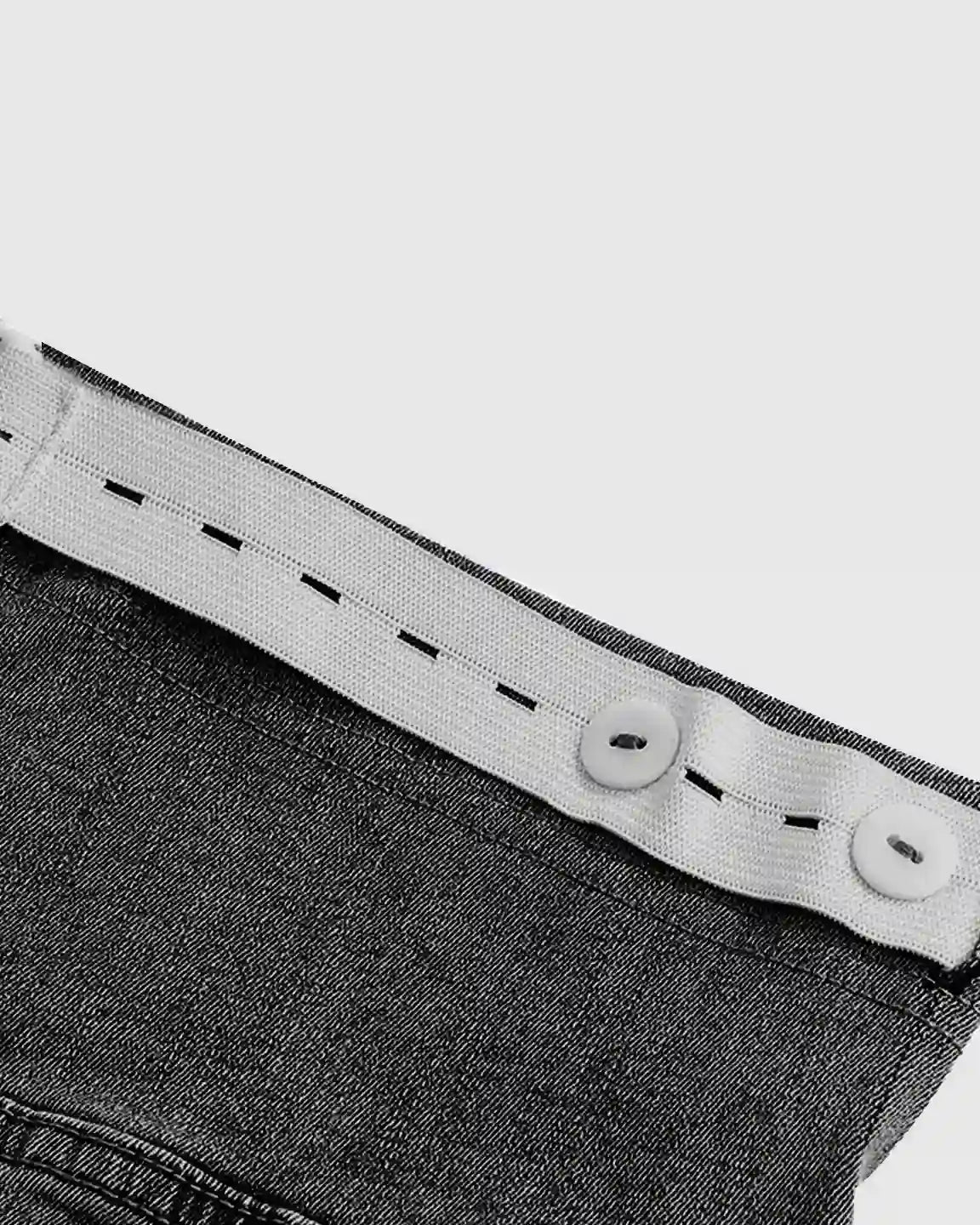 Close-up of dark wash maternity jeans with adjustable white elastic waistband and buttons.