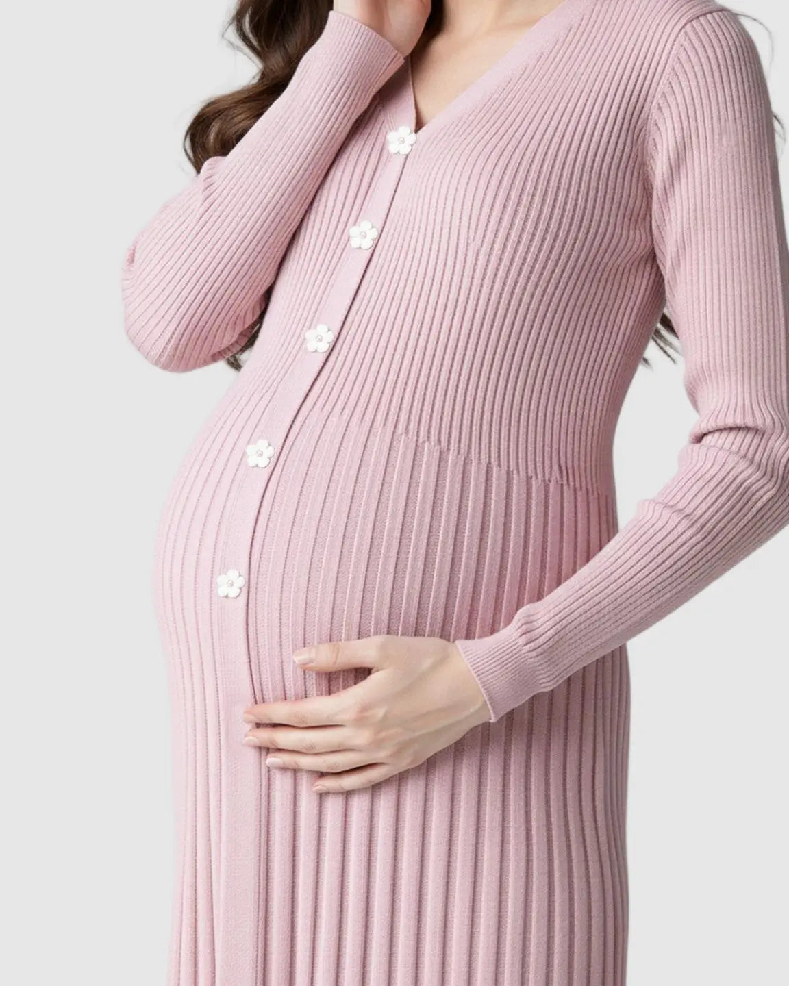 Pregnant woman in a pink ribbed knit maternity midi dress with white flower buttons and V-neck.