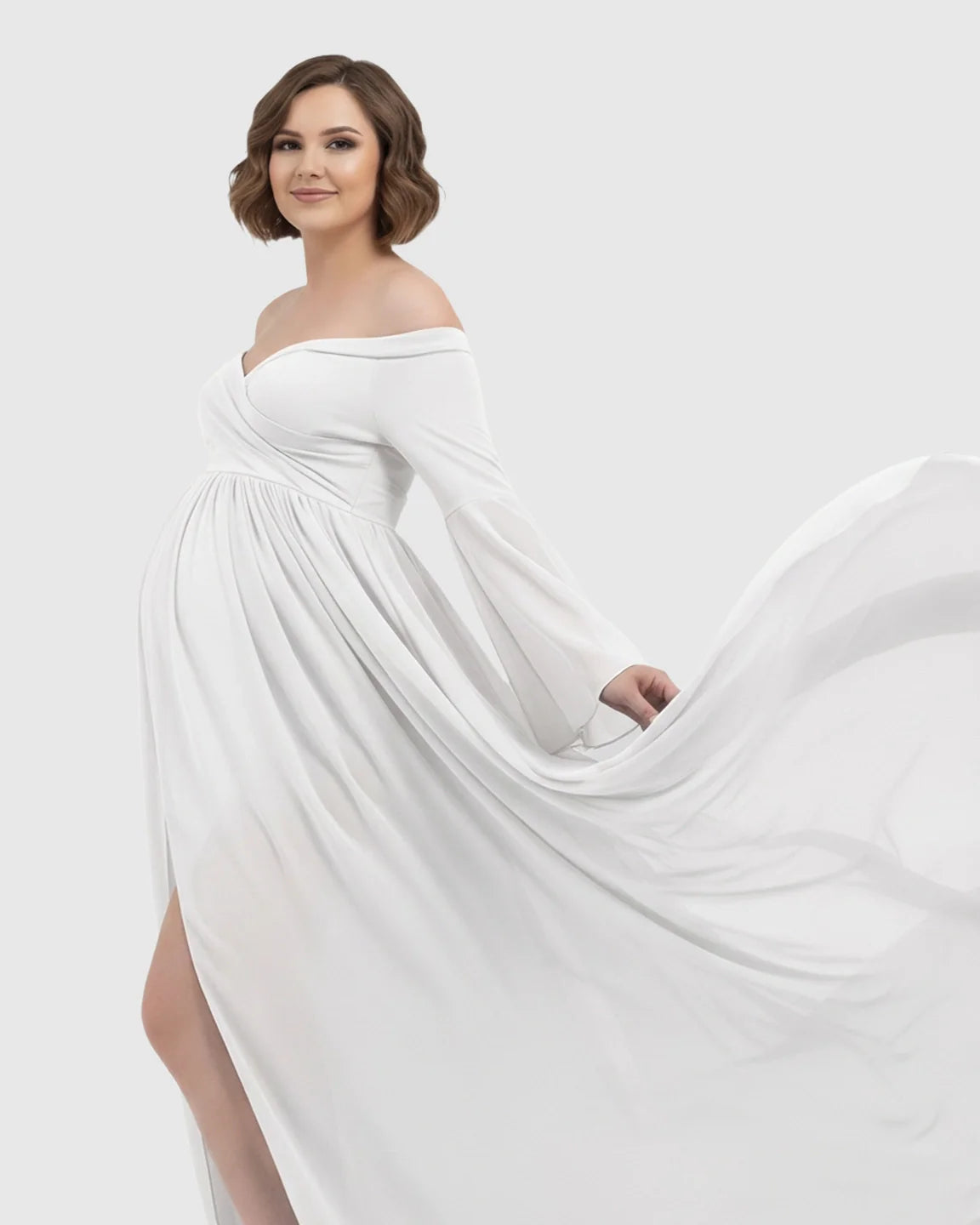 White off-shoulder maternity gown with bell sleeves and a long flowing train.