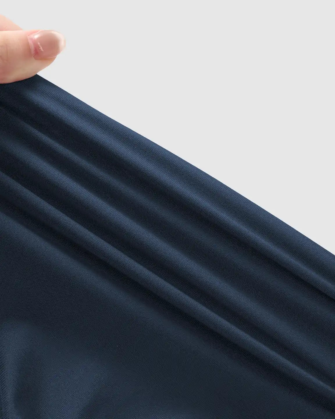 Hand stretching soft, dark navy blue maternity jogger fabric, highlighting its breathable, stretchy material.