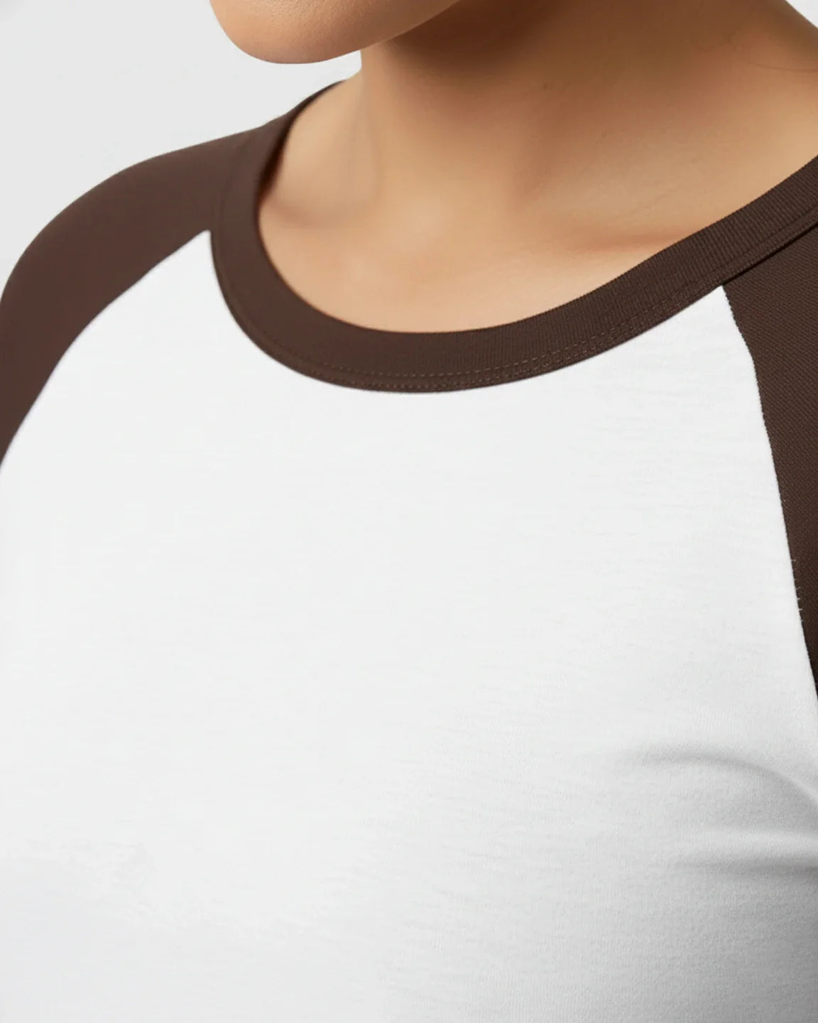 Close-up of a white maternity top with brown raglan sleeves and a brown crew neck, made from smooth, high-elastic polyester.