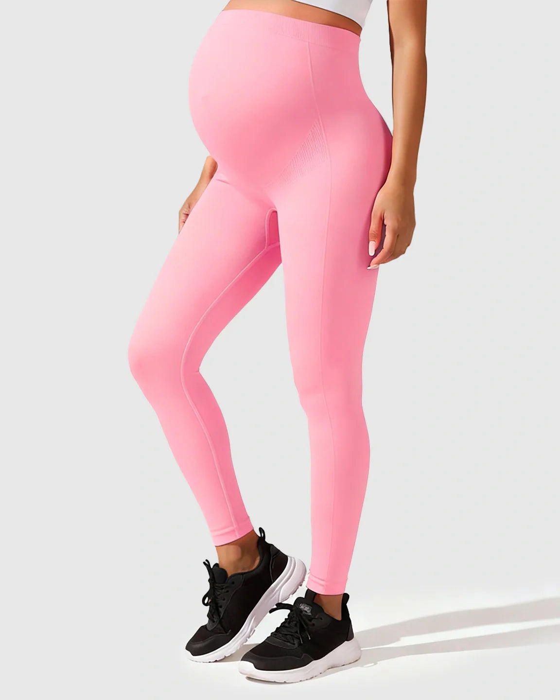 Seamless pink M-shape maternity leggings with full-belly support, worn by a pregnant model.
