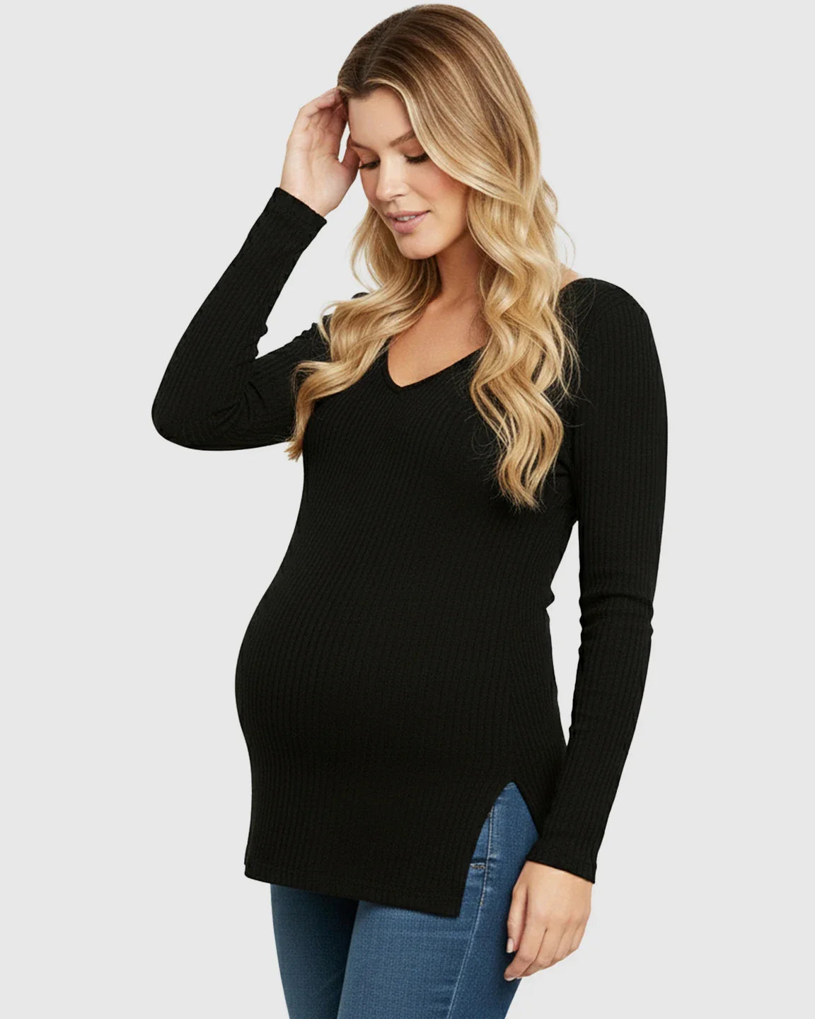 Pregnant woman in a black ribbed V-neck long sleeve maternity top with side slits, paired with jeans.