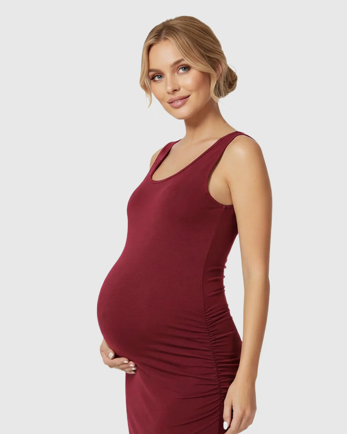 Pregnant woman in a red sleeveless bodycon maternity dress with side ruching, smiling.
