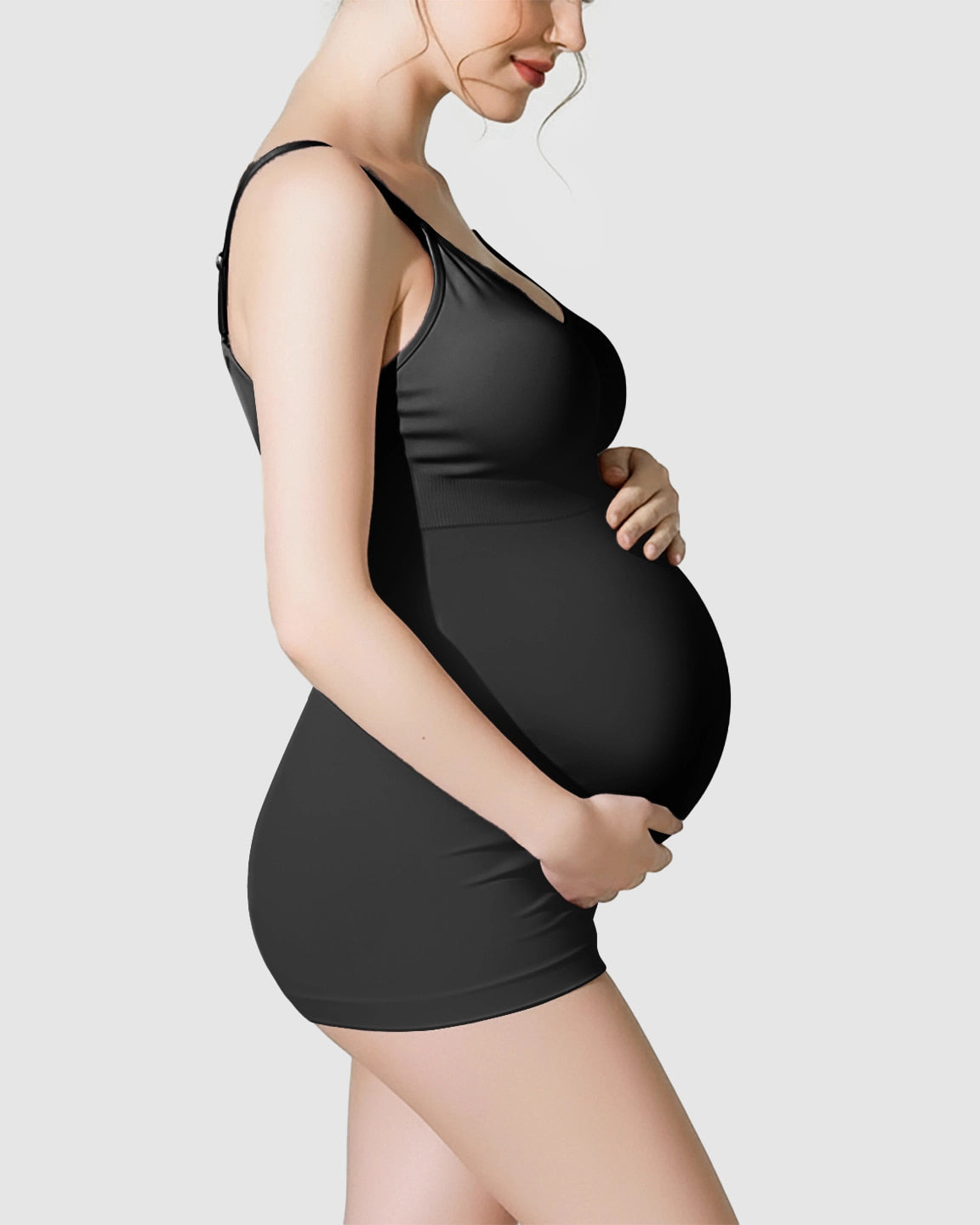 Pregnant woman in a black soft stretch maternity nursing bra and matching shorts, cradling her belly.