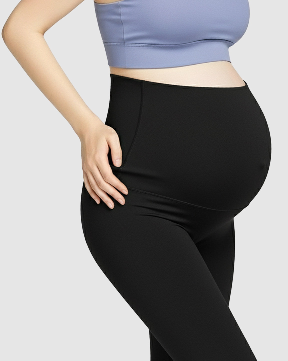 Pregnant woman wearing black high-waist soft stretch maternity leggings and a periwinkle sports bra.