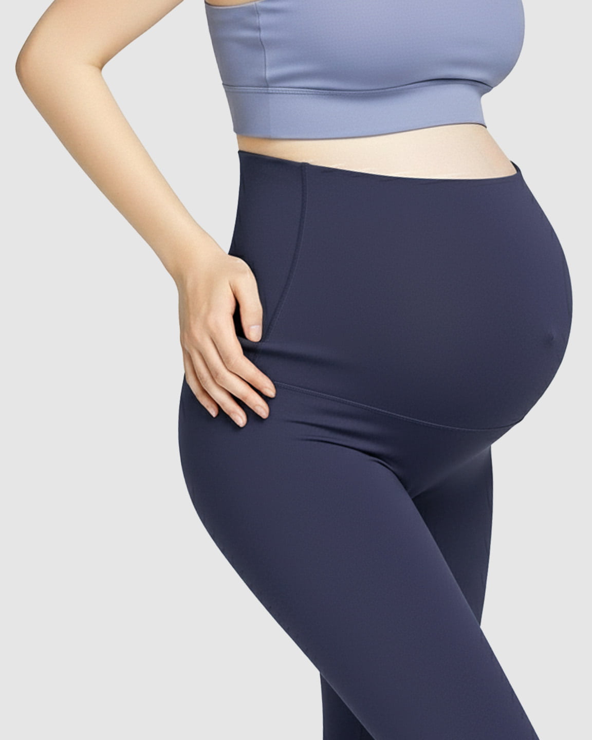 Pregnant woman wearing high-waist navy soft stretch maternity leggings and a light blue bra.