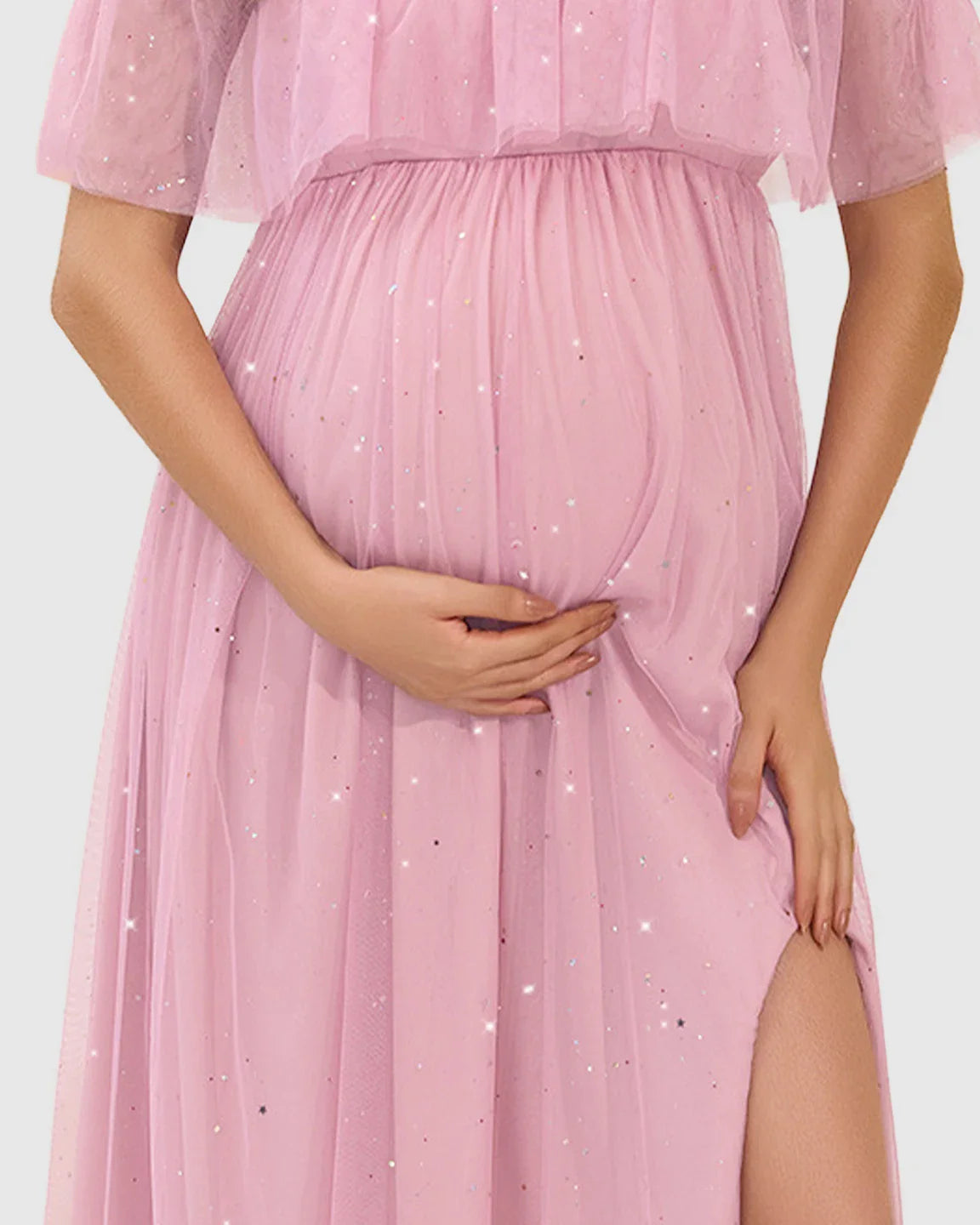 Pink off-shoulder mesh maternity gown with a flutter neckline, high slit, and sparkling details.