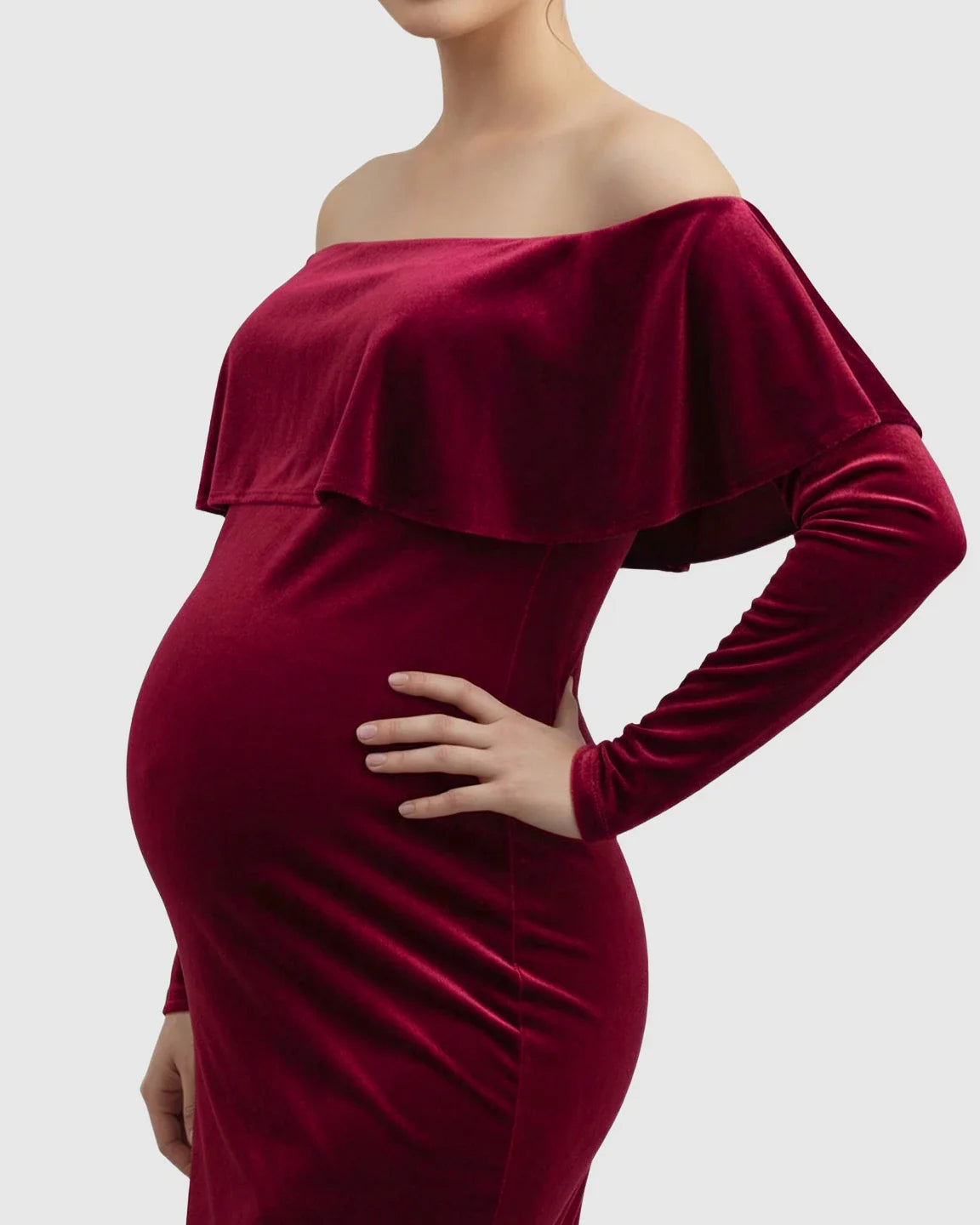 Velvet-touch elegant fitted maternity photoshoot gown in deep red, off-shoulder with long sleeves, highlighting the bump.