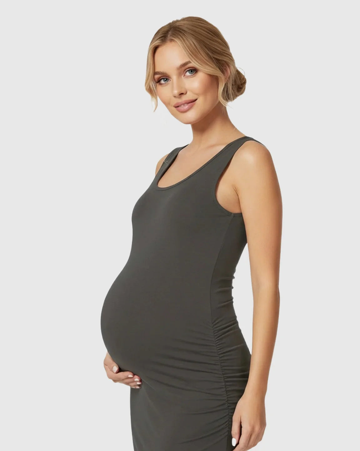 Smiling pregnant woman in a dark gray sleeveless bodycon maternity dress with side ruching.
