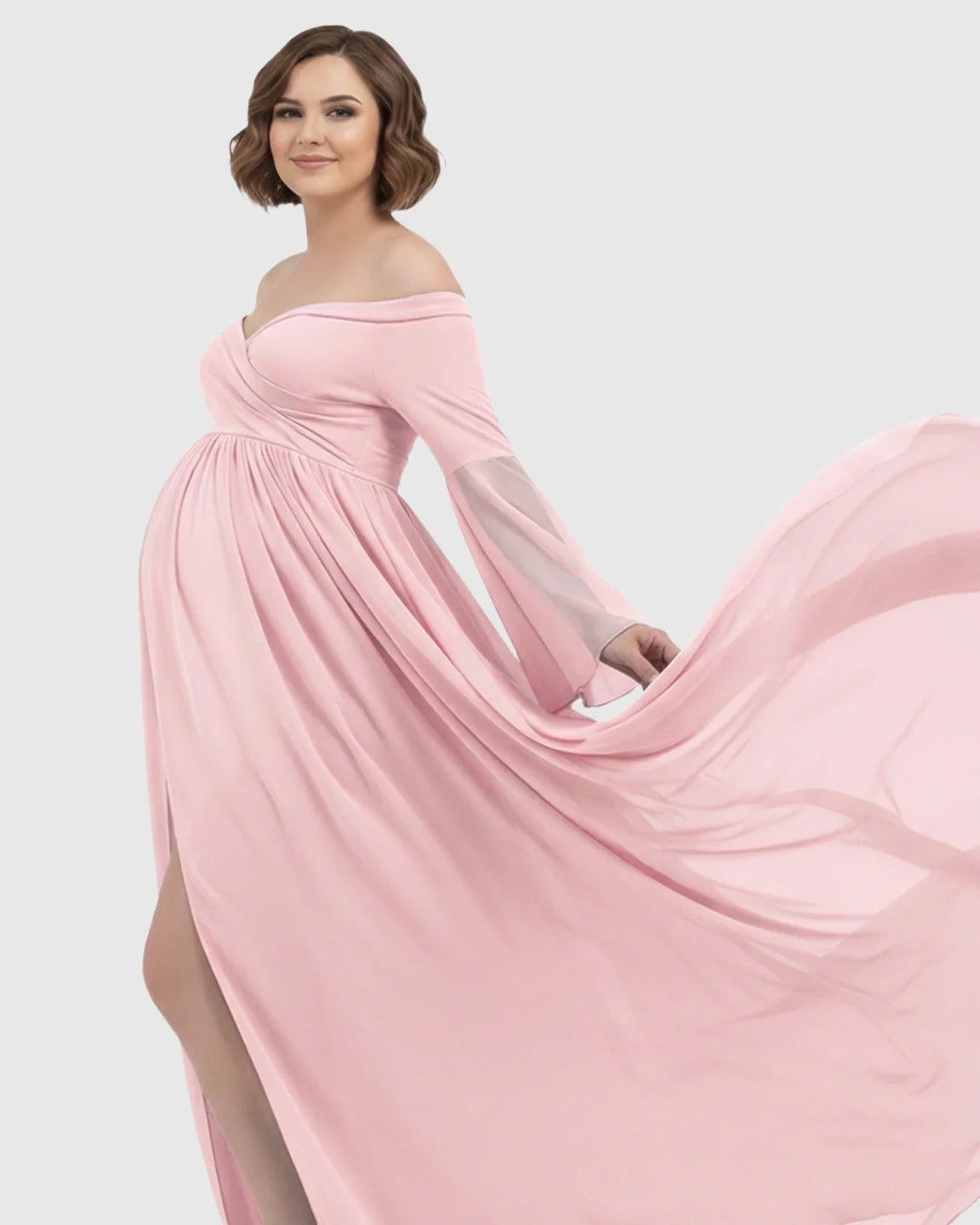 Pink off-shoulder maternity photoshoot gown with bell sleeves, long flowing chiffon train, and side slit.