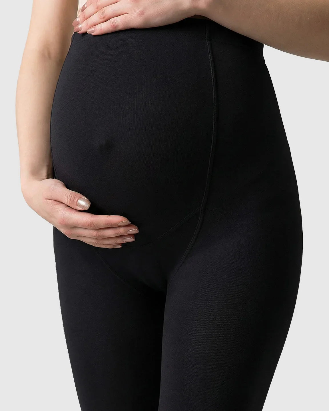 Black fleece-lined over-bump maternity leggings with a pregnant woman's hands cradling her belly.