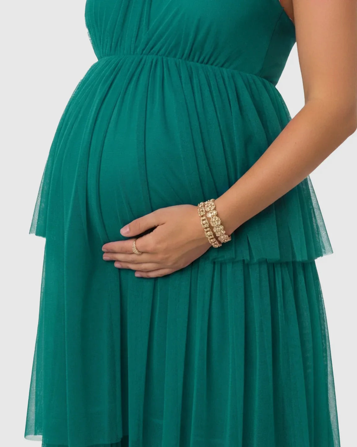Emerald green halter neck tiered mesh maternity gown, flattering a pregnant belly.