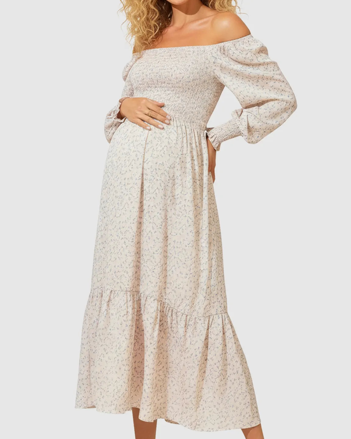 Off-shoulder flowy maternity midi dress in light pink floral print with smocked bodice and tiered skirt.