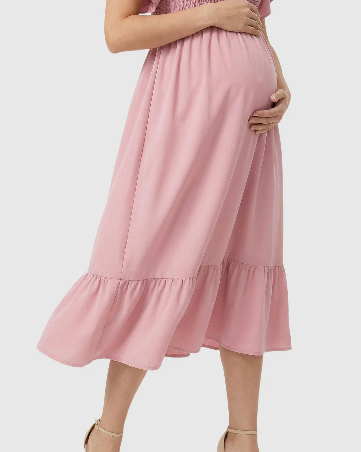 Pink flutter-sleeve smocked maternity midi dress with tiered skirt, worn by an expecting mom.