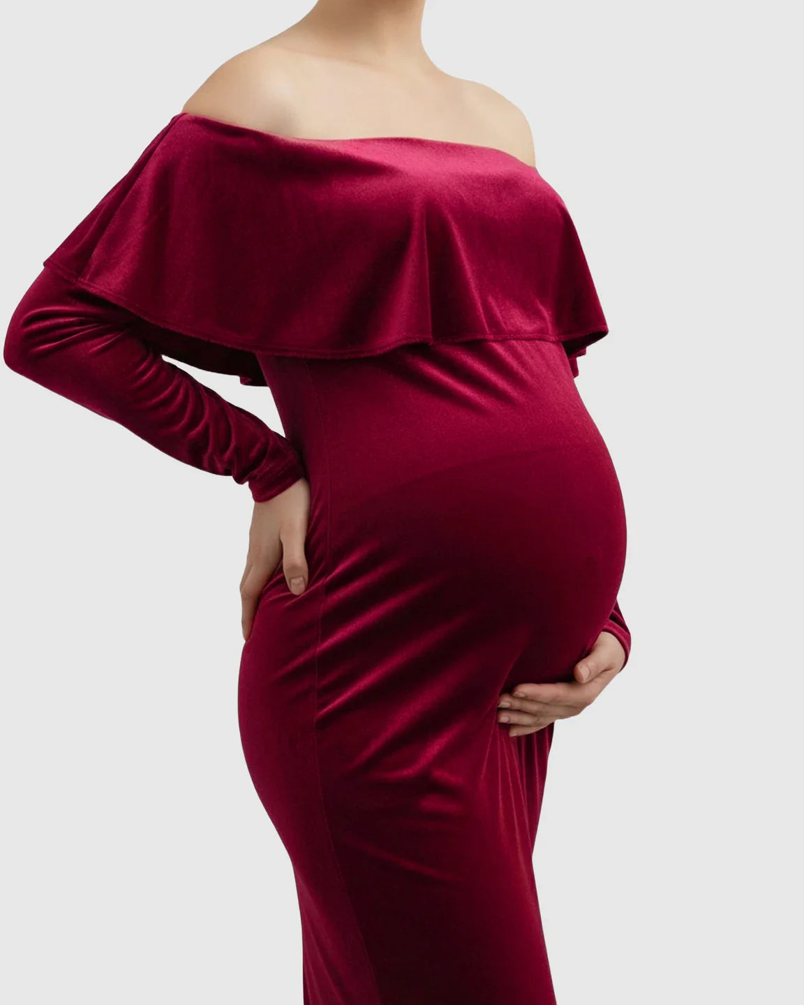 Velvet-touch elegant fitted maternity photoshoot gown in deep red, featuring an off-shoulder ruffle and long sleeves.