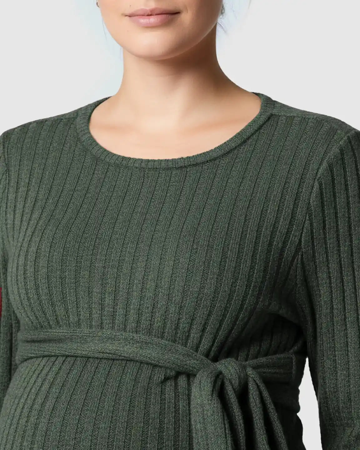 Close-up of a pregnant woman wearing a dark green ribbed maternity sweater with a tie-waist.