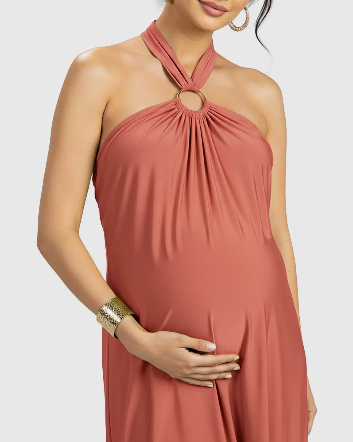 Maternity maxi dress in terracotta chiffon with a halter neck and gold ring detail, flattering a pregnant belly.