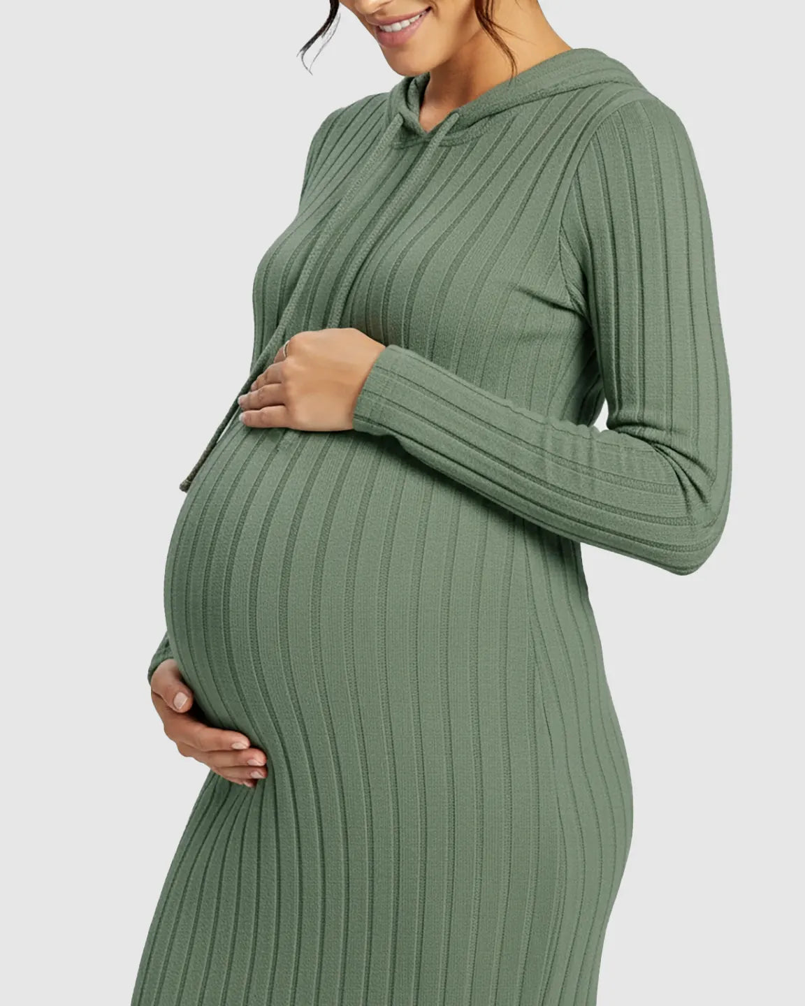 Pregnant woman in a green ribbed bodycon hooded maternity midi dress, gently holding her bump.