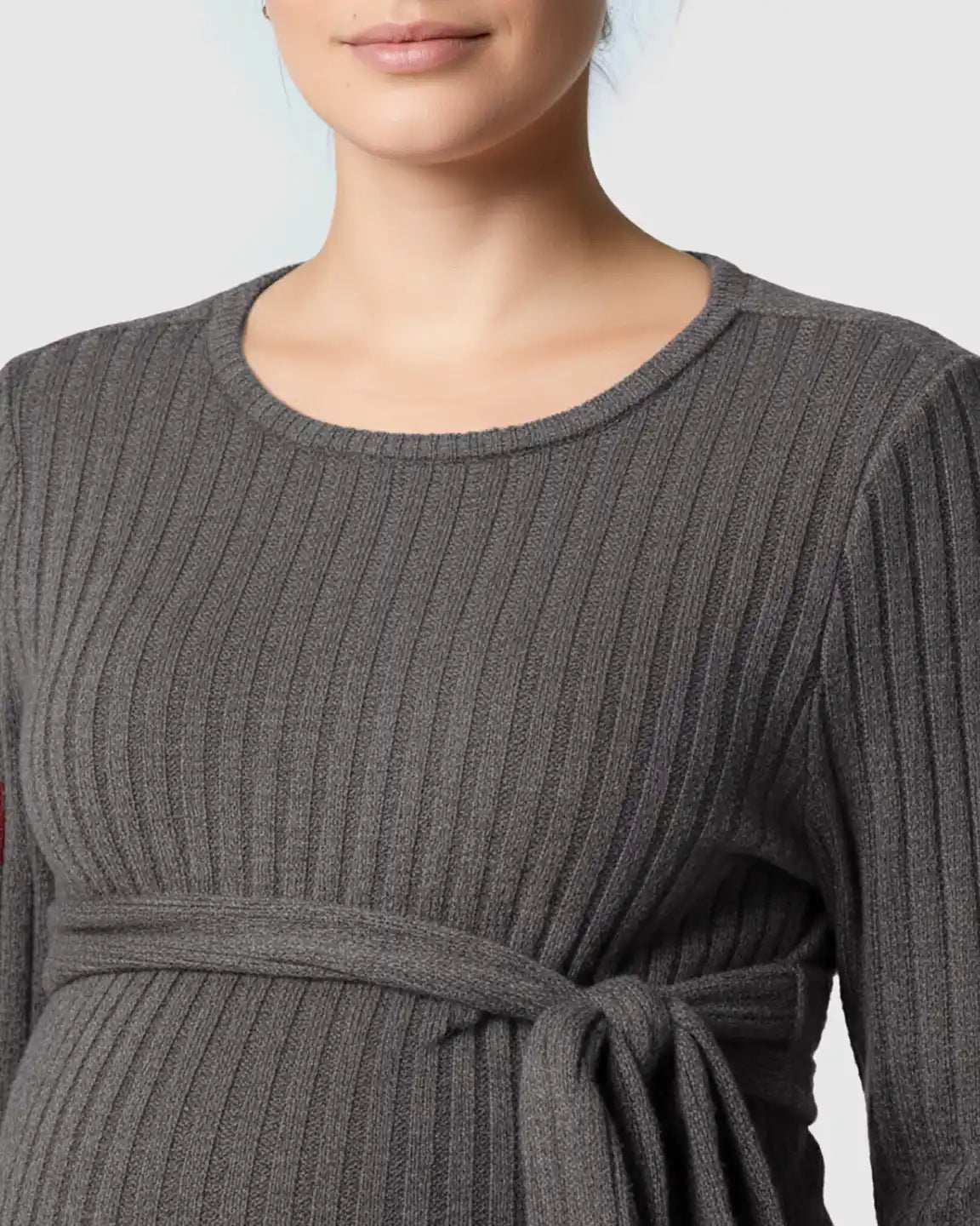 Close-up of a woman wearing a dark gray ribbed maternity sweater with a tie-waist.