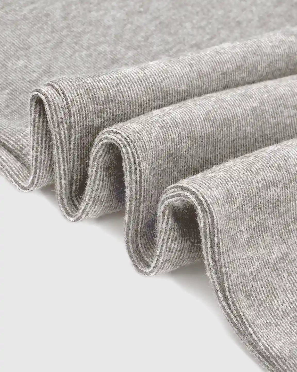 Close-up of soft, heather gray knit fabric, folded to show its comfortable texture and stretch.