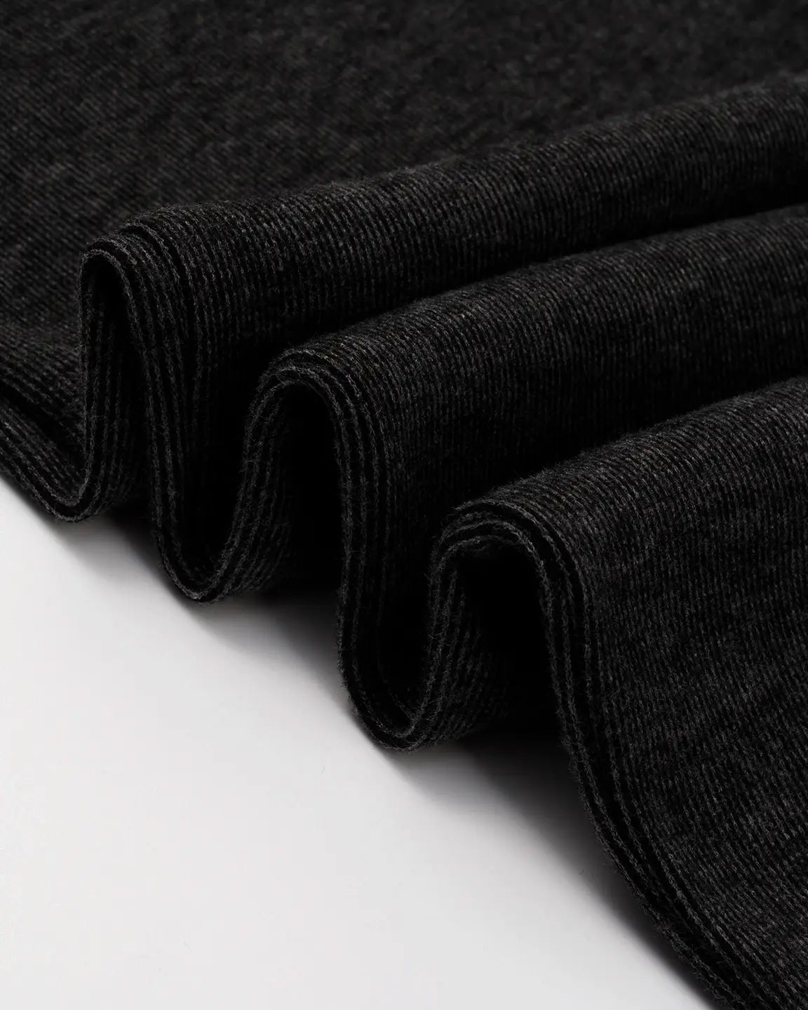 Close-up of dark gray, ribbed knit maternity pants fabric, showing soft texture and gentle folds.