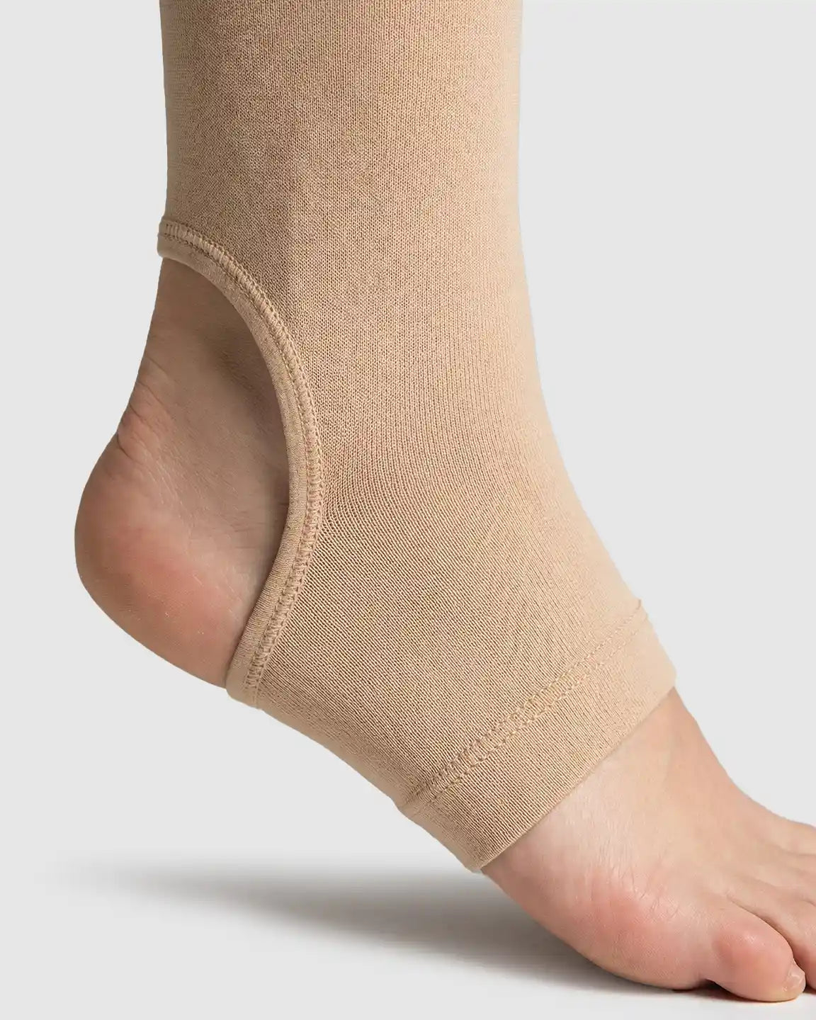 Close-up of a foot wearing a beige fleece-lined maternity legging with a secure stirrup design.