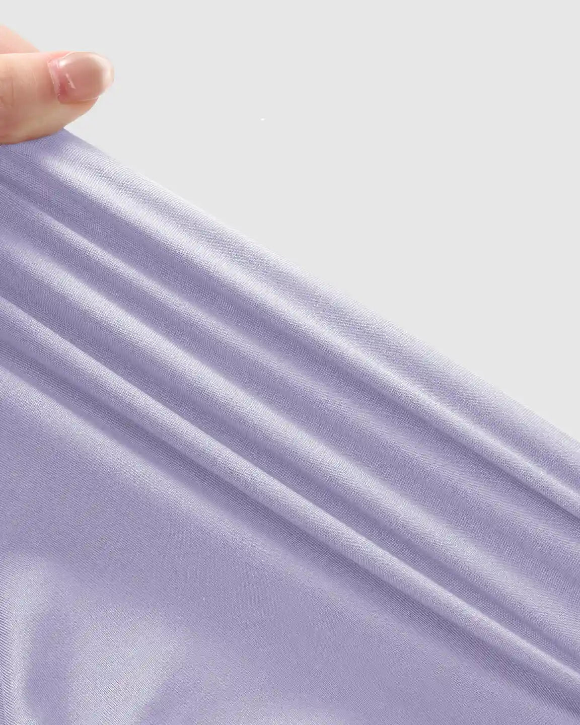 Hand stretching light purple, soft, high-waist maternity jogger fabric, highlighting its gentle support and stretch.