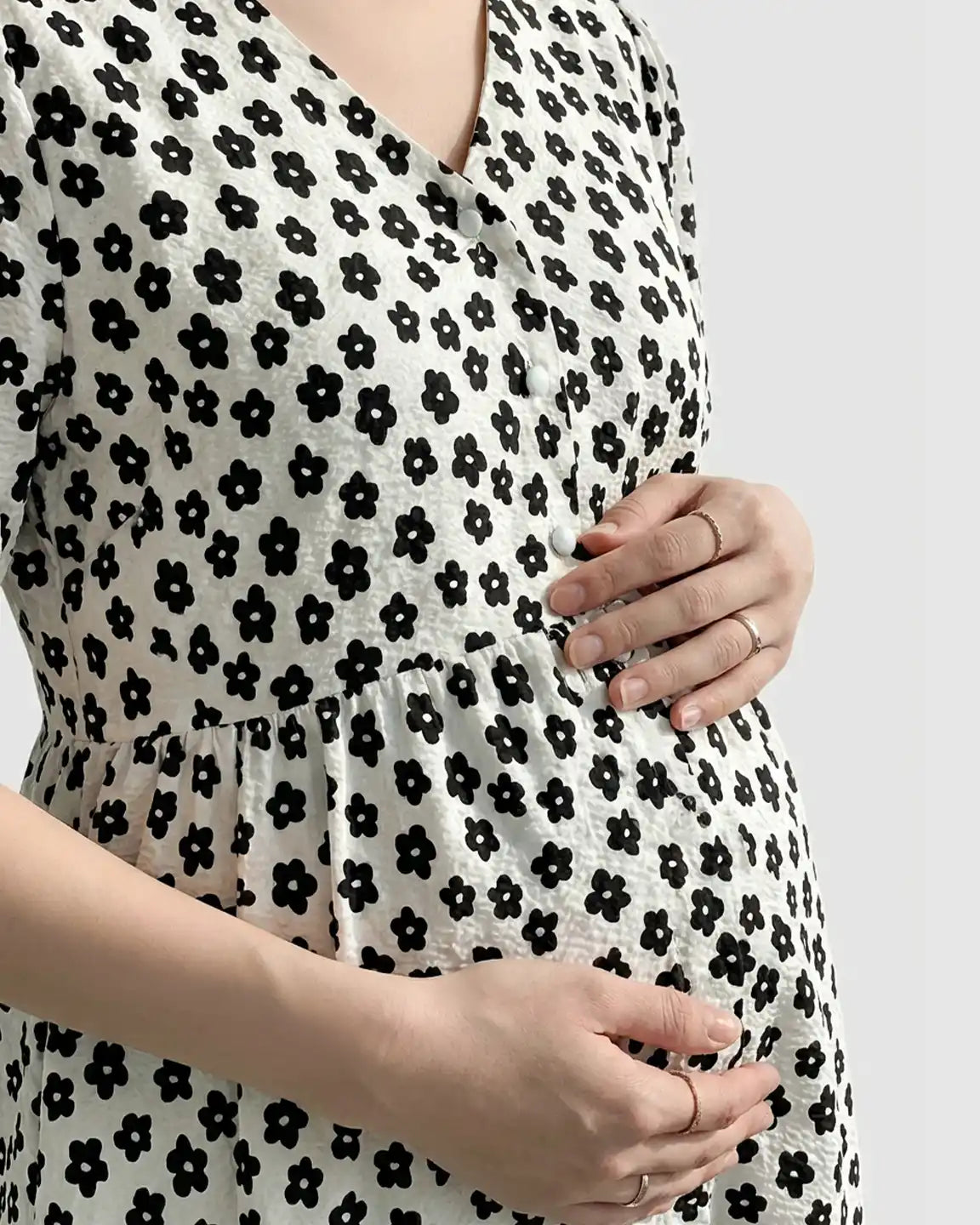 White maternity nursing dress with black floral print, V-neck, and partial button-front.