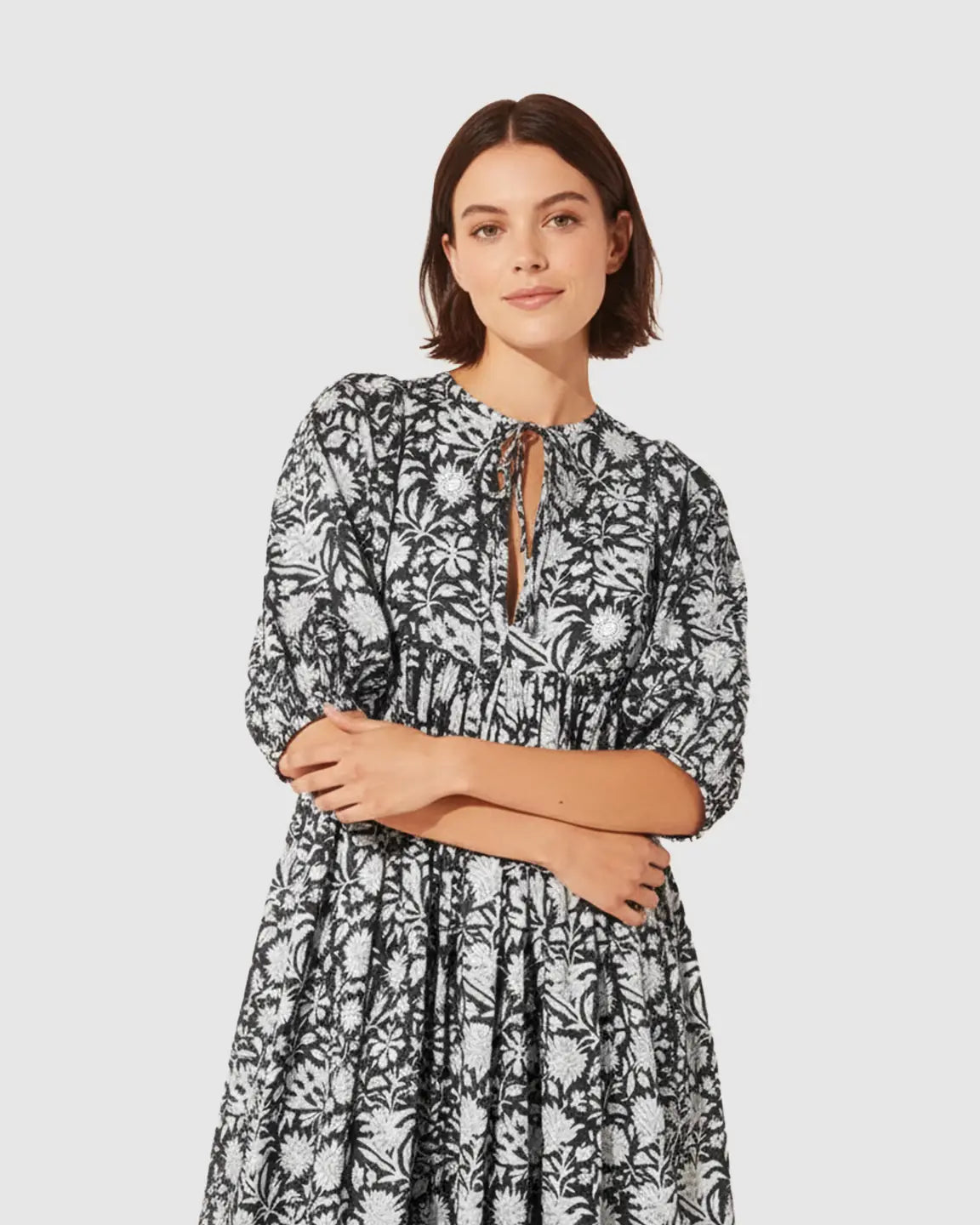 Woman in black and white floral loose-fit maternity midi dress with gathered shoulders and puff sleeves.