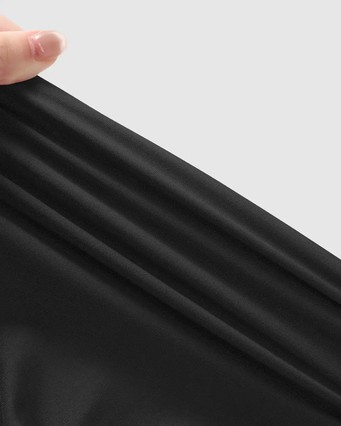 Hand stretching soft, black, supportive maternity jogger fabric, highlighting its gentle stretch and texture.