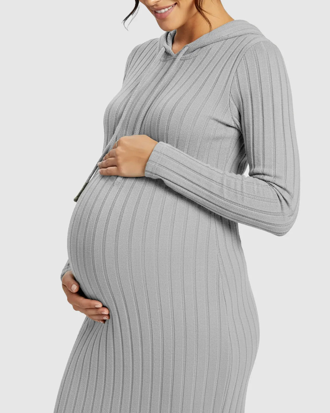 Pregnant woman in a gray ribbed bodycon hooded maternity midi dress, gently holding her bump.