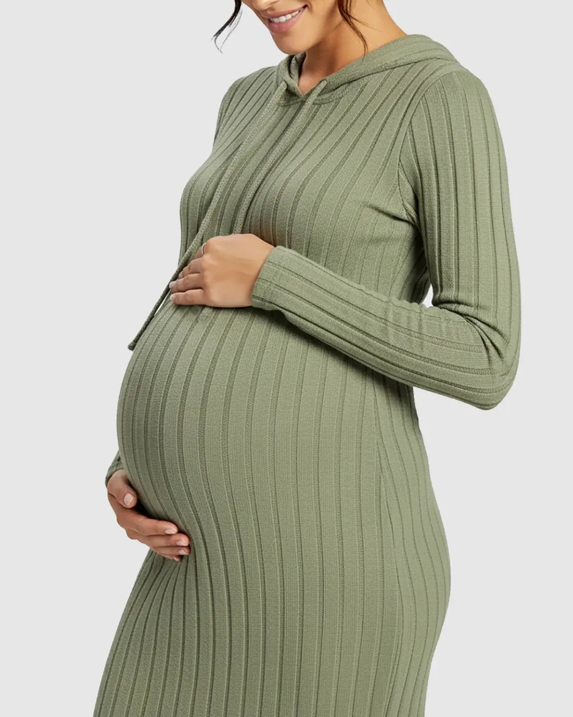 Pregnant woman in a green ribbed bodycon hooded maternity midi dress, gently holding her bump.