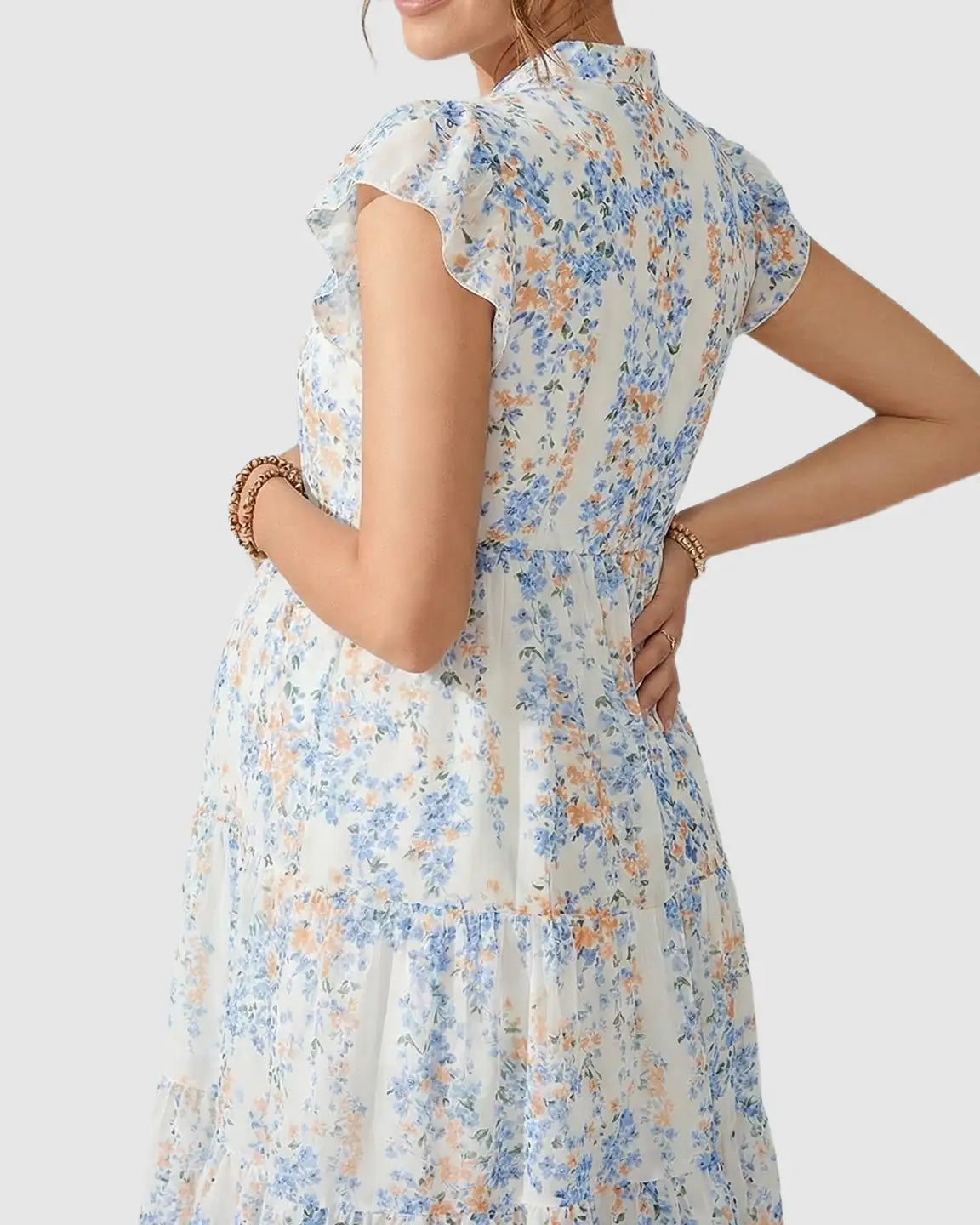 White chiffon A-line maternity dress with blue and orange floral print and flutter sleeves.