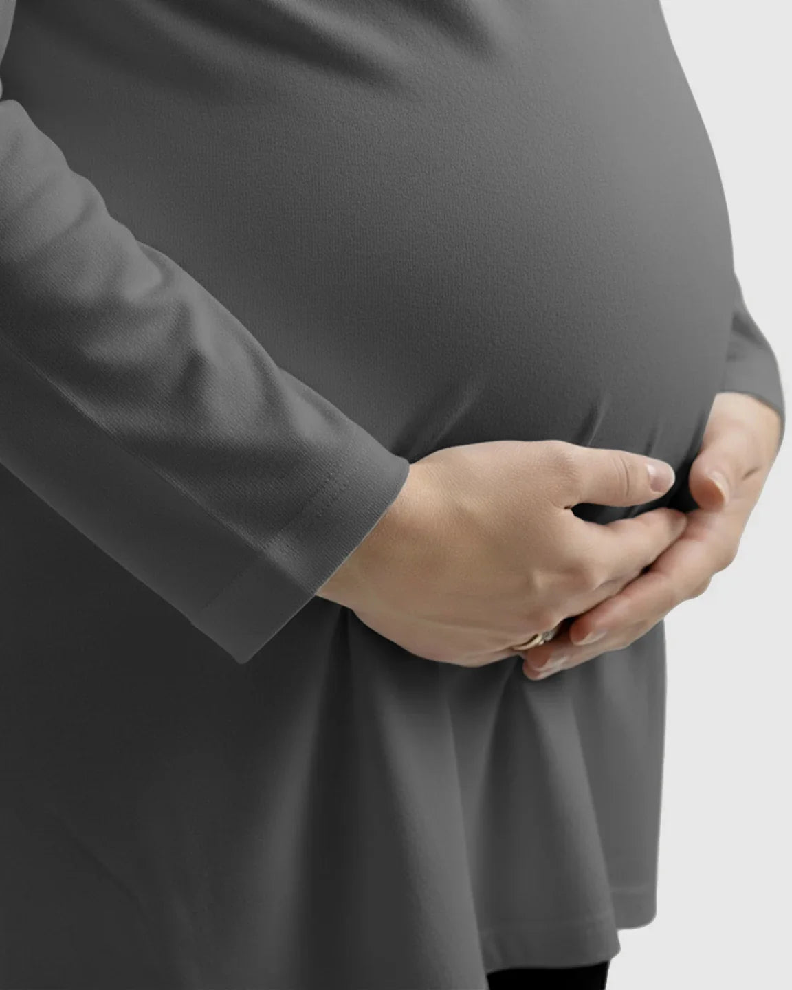 Pregnant woman wearing a soft, dark gray long-sleeve cotton maternity top, hands gently cradling her bump.