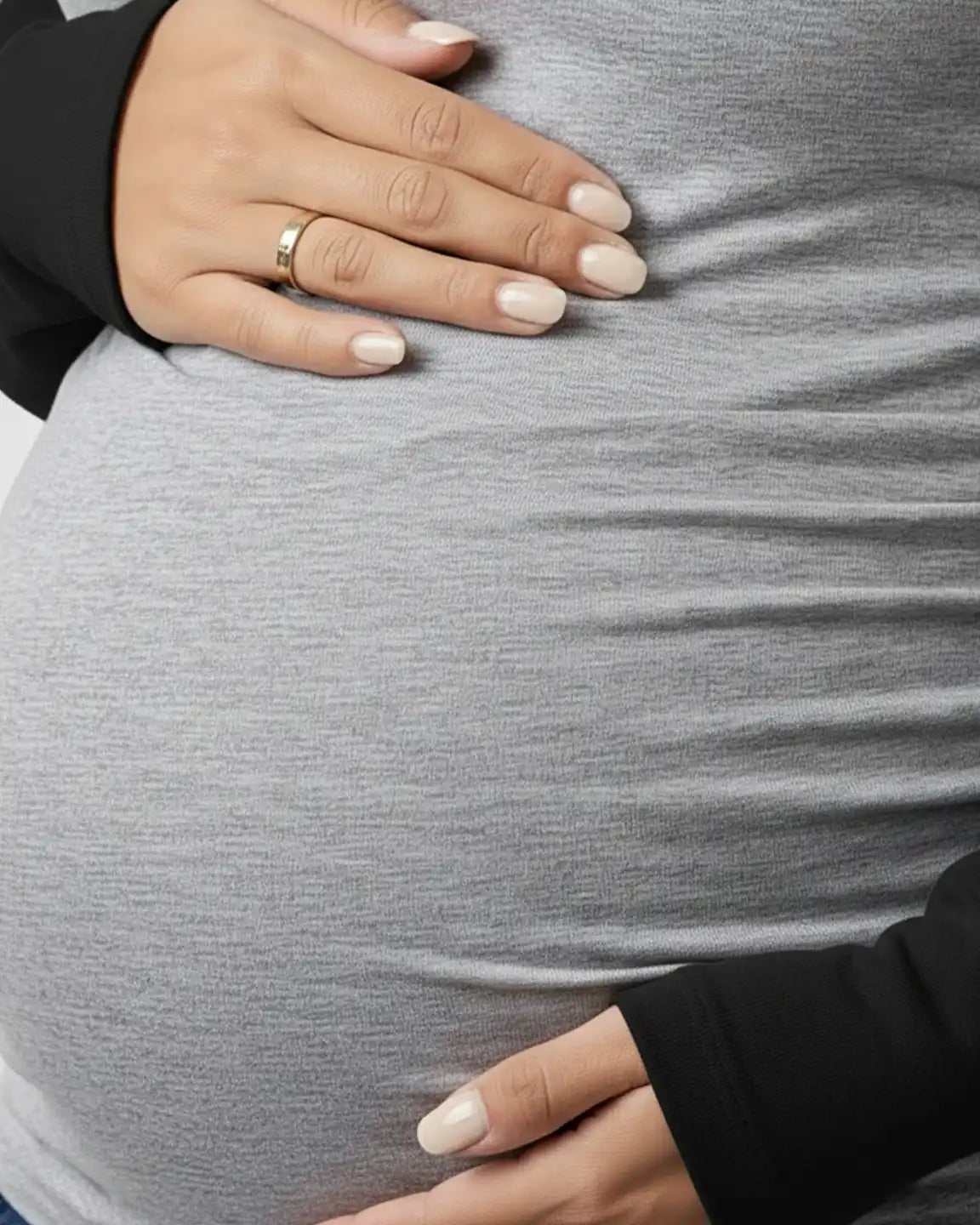 Pregnant belly in a gray stretch-fit long-sleeve maternity top with black raglan sleeves and side ruching.