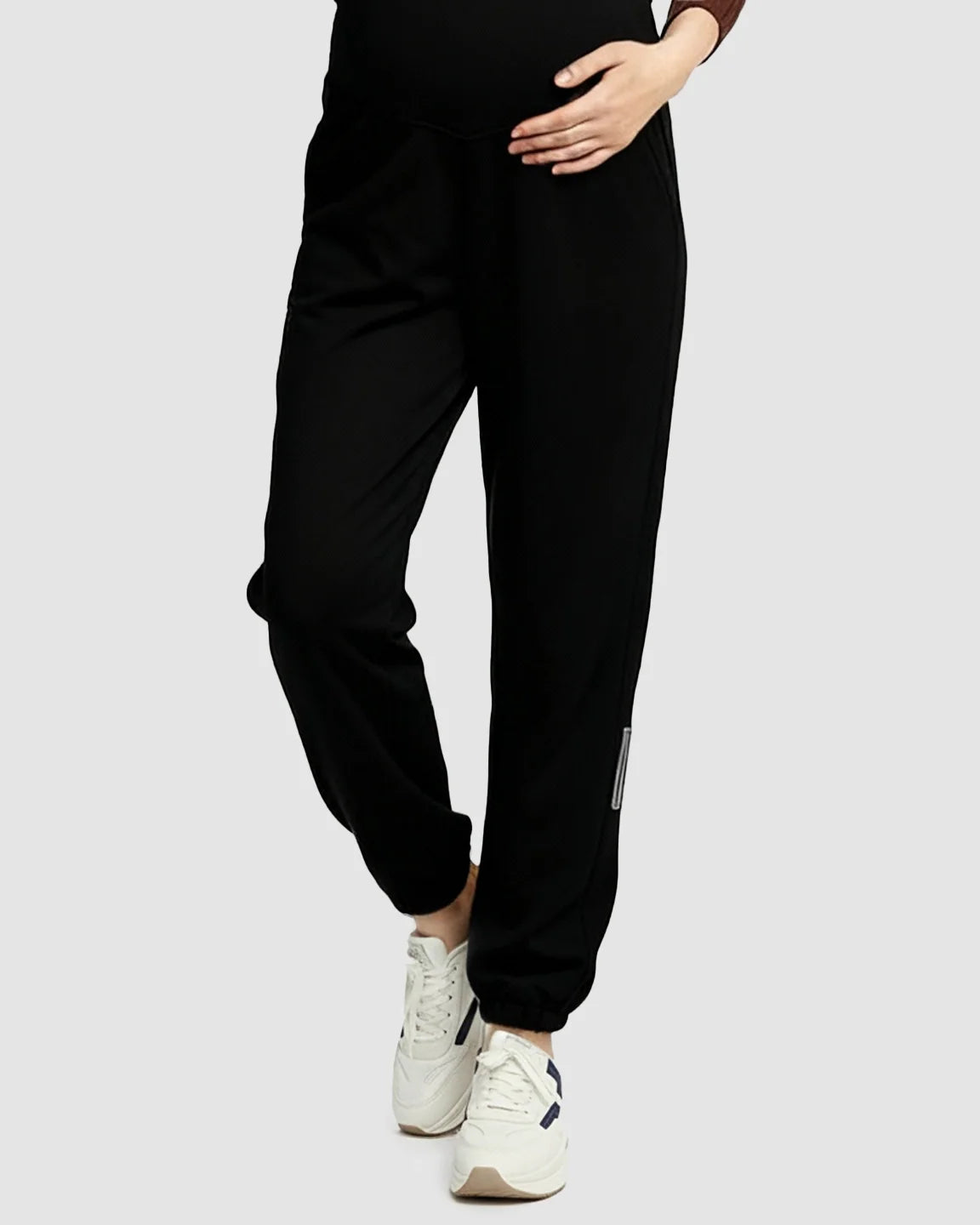 Black soft knit maternity joggers with pockets and a supportive waistband, worn with white sneakers.