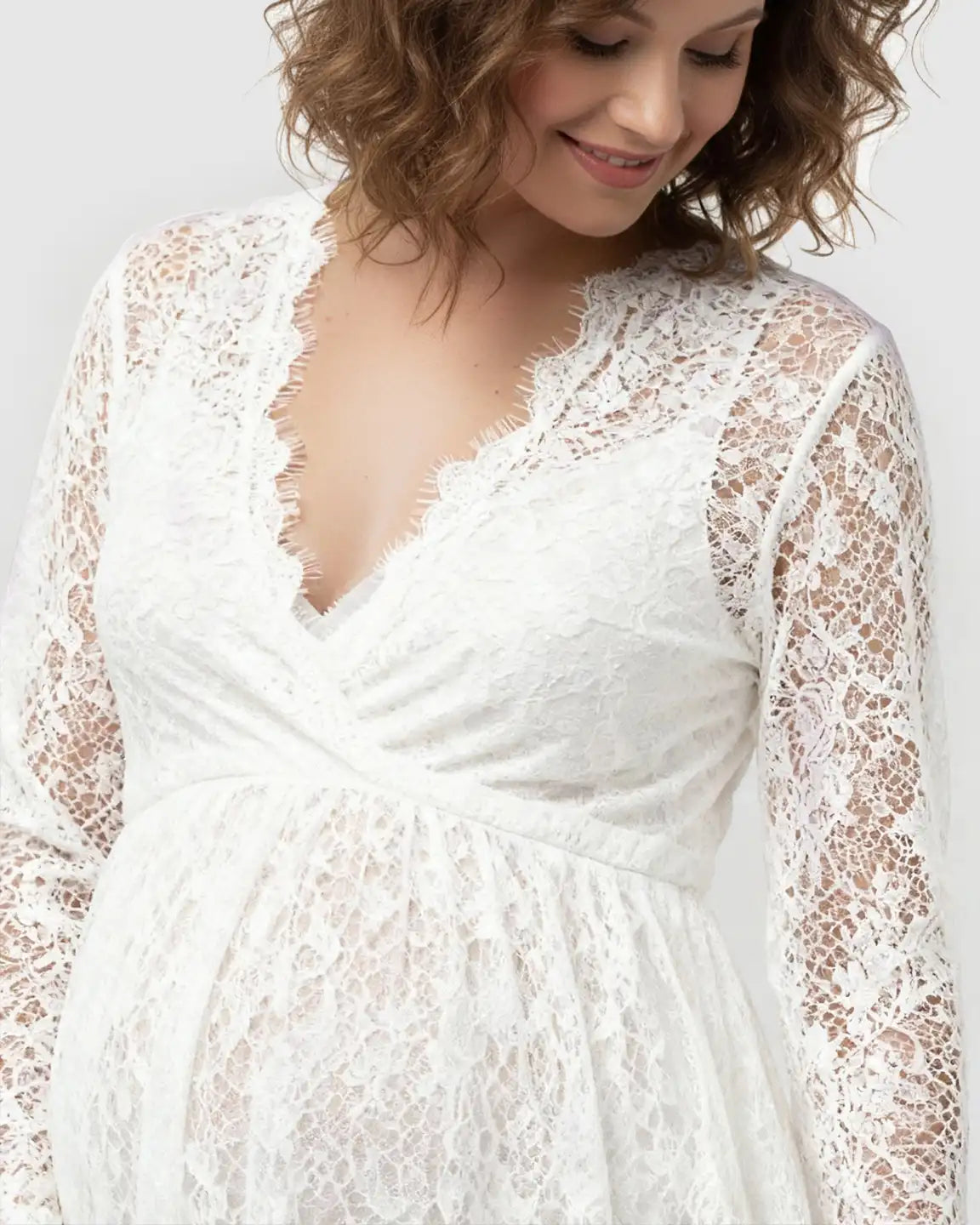 Maternity maxi dress in white sheer floral lace with a V-neck, empire waist, and long sleeves.