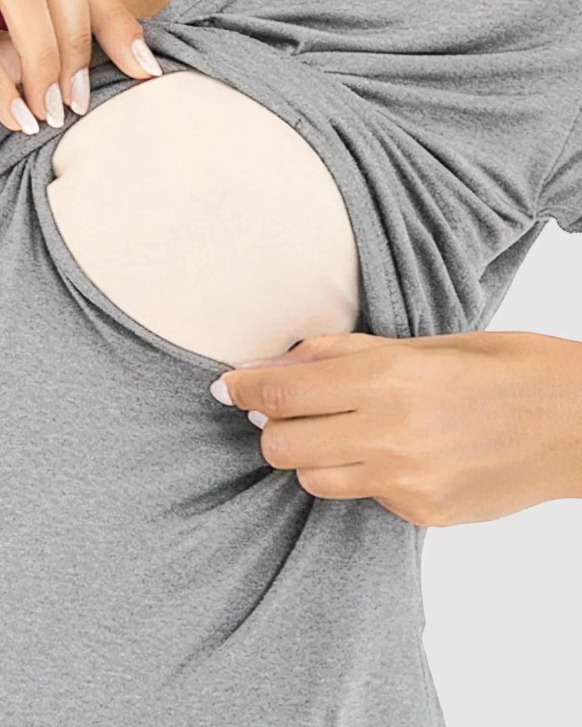 Hands demonstrating the easy breastfeeding access of a gray wrap V-neck maternity and nursing top.