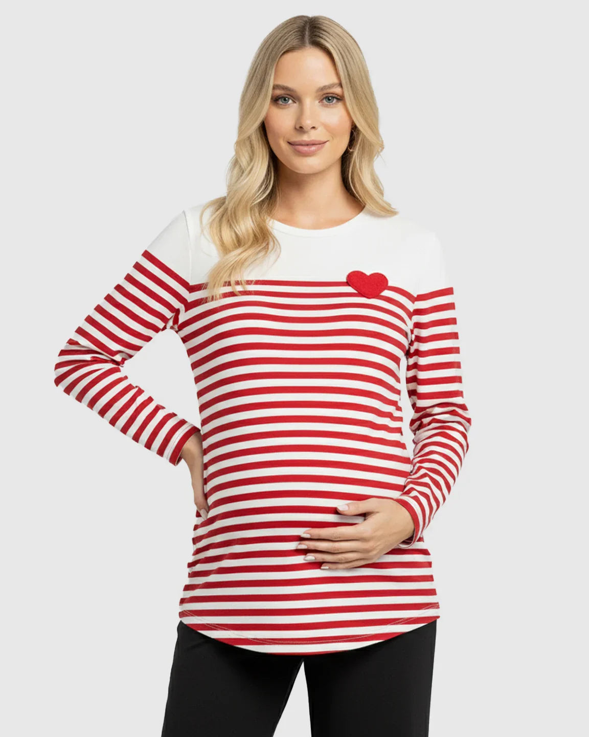 Blonde pregnant woman in a red and white striped long-sleeve maternity top with an embroidered red heart.