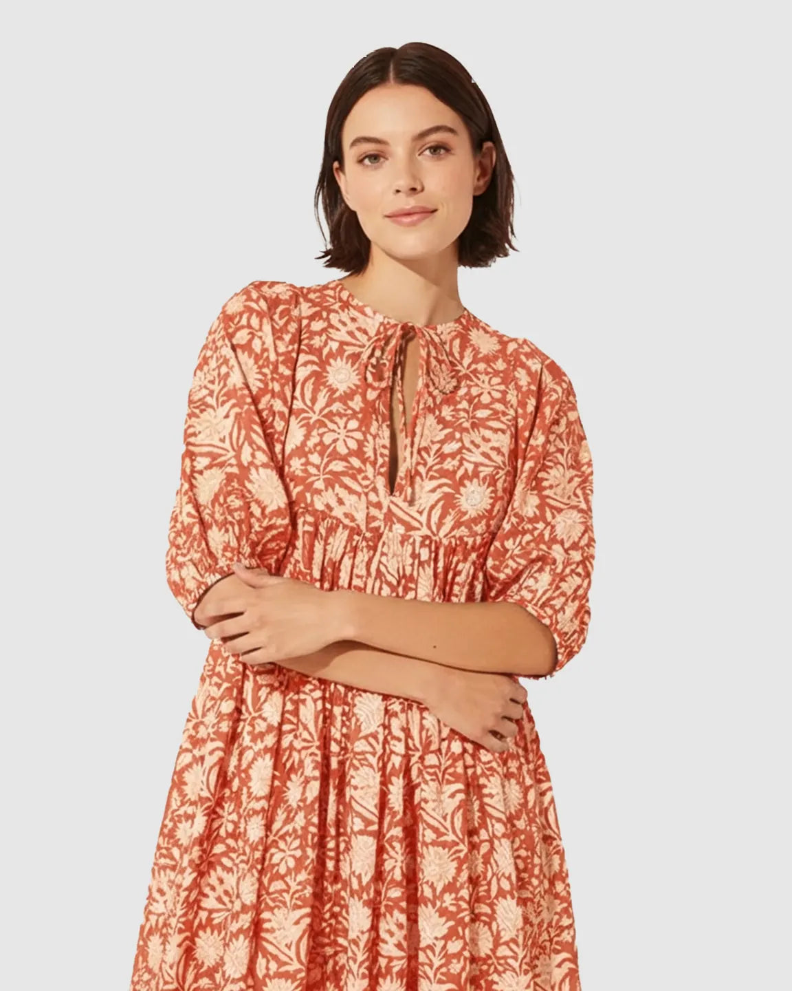 Woman in a rust floral loose-fit maternity midi dress with gathered shoulders and puff sleeves.