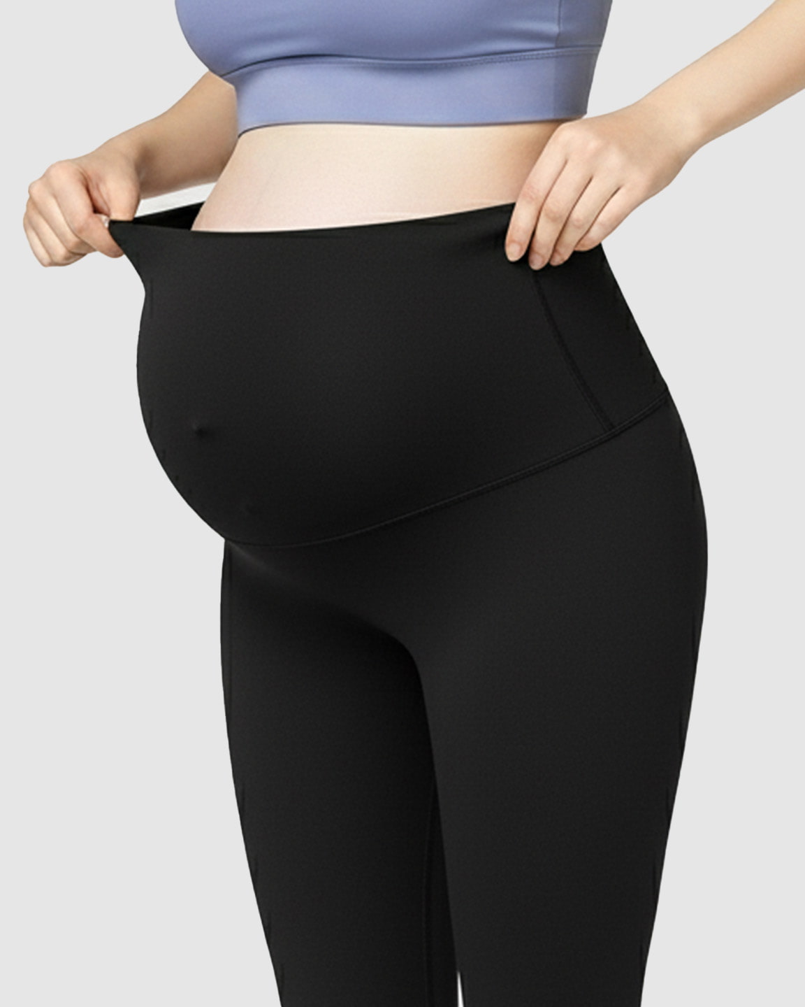 Pregnant woman adjusting the high-waist, black soft stretch maternity leggings for bump support.