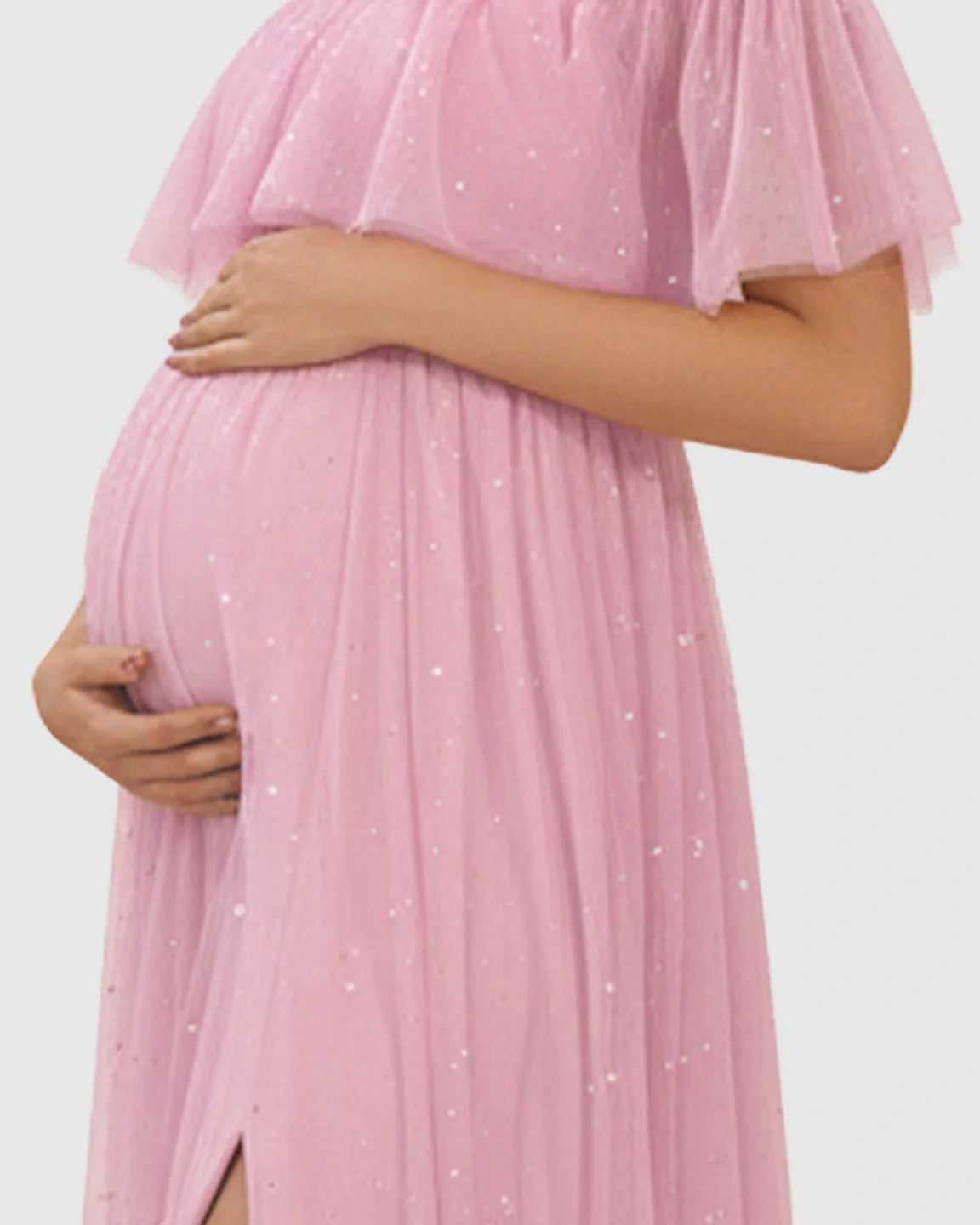 Pink off-shoulder mesh maternity gown with flutter neckline, high slit, and glitter accents.