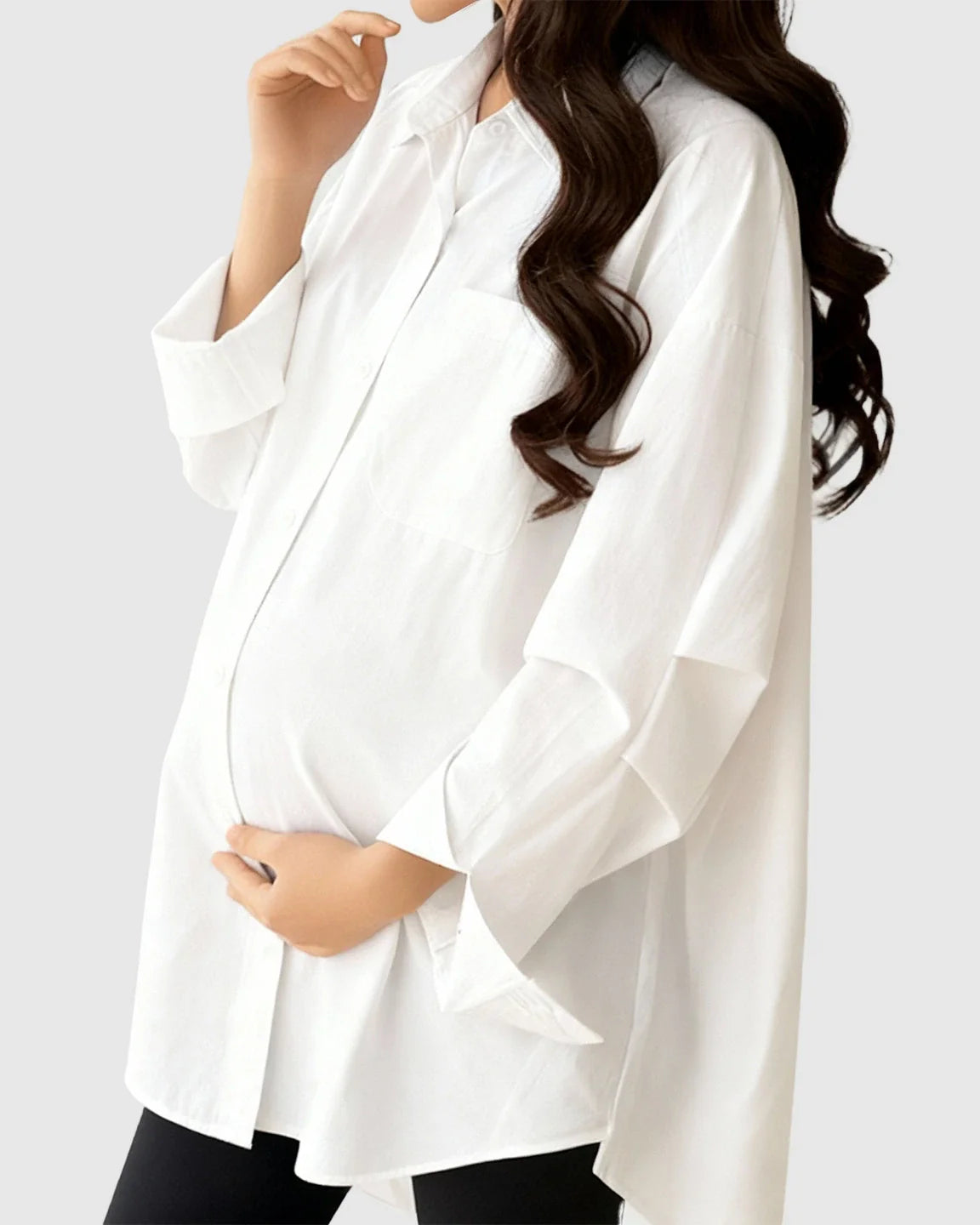 Pregnant woman wearing a white cotton lapel-collar button-front maternity tunic.