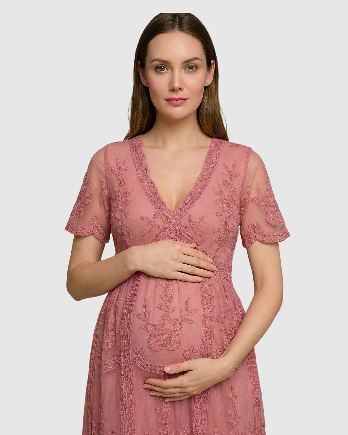 Maternity model in a pink lace V-neck midi dress with three-quarter sleeves and floral embroidery.