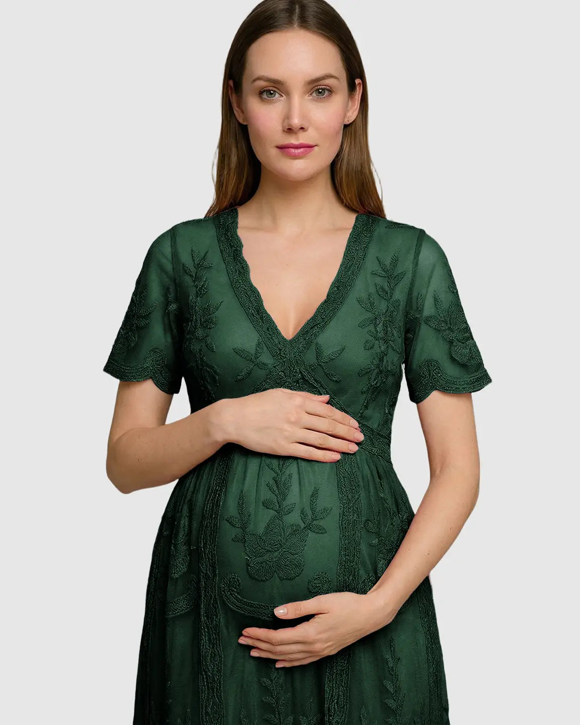 Maternity midi dress in dark green lace with V-neck, three-quarter sleeves, and swing skirt, worn by a pregnant woman.