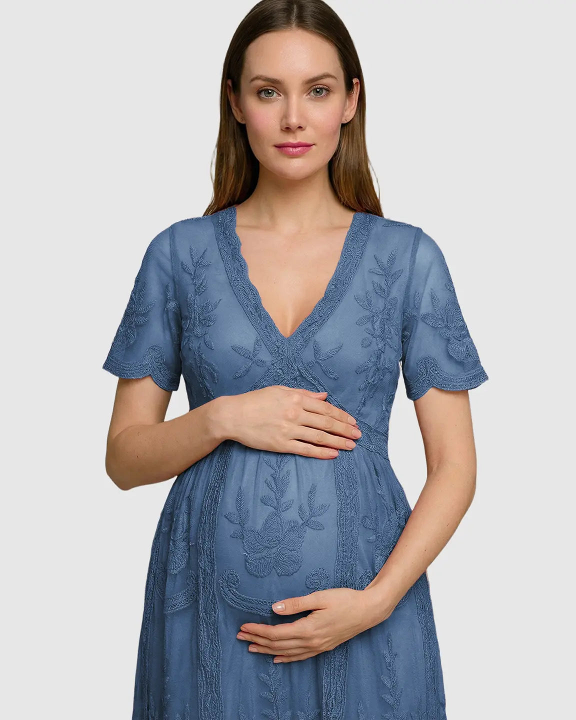 Maternity midi dress in dusty blue lace with V-neck, three-quarter sleeves, and swing skirt, worn by a pregnant woman.