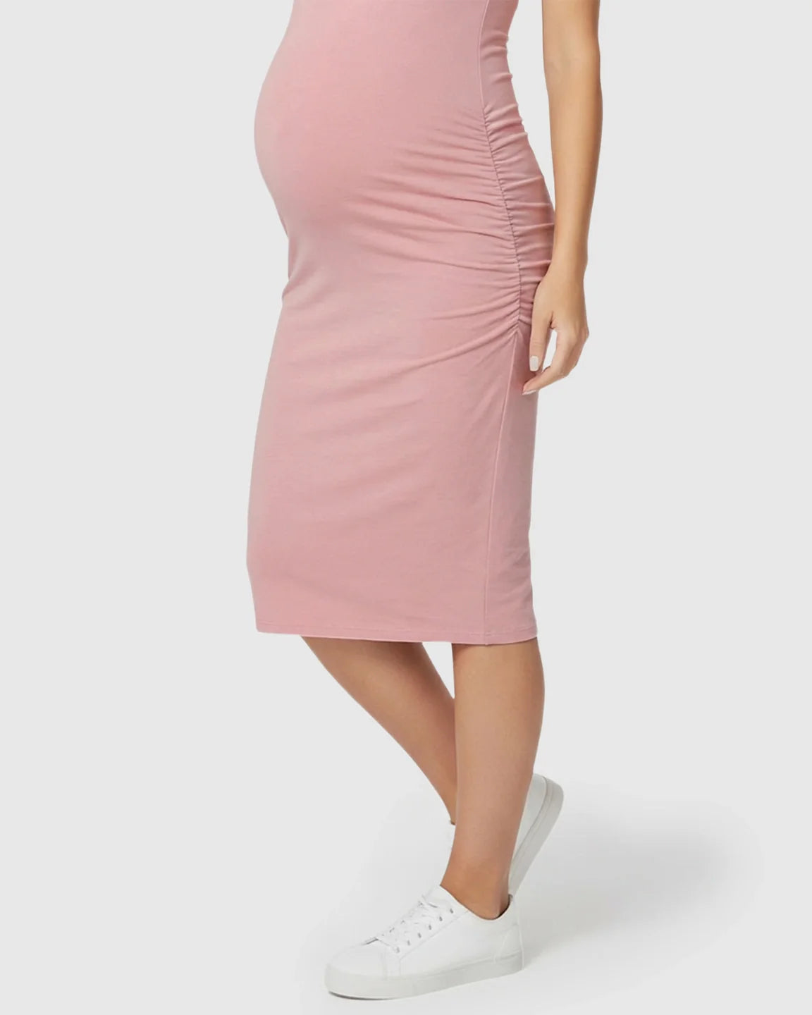 Pink sleeveless bodycon maternity dress with side ruching, worn by a pregnant model with white sneakers.