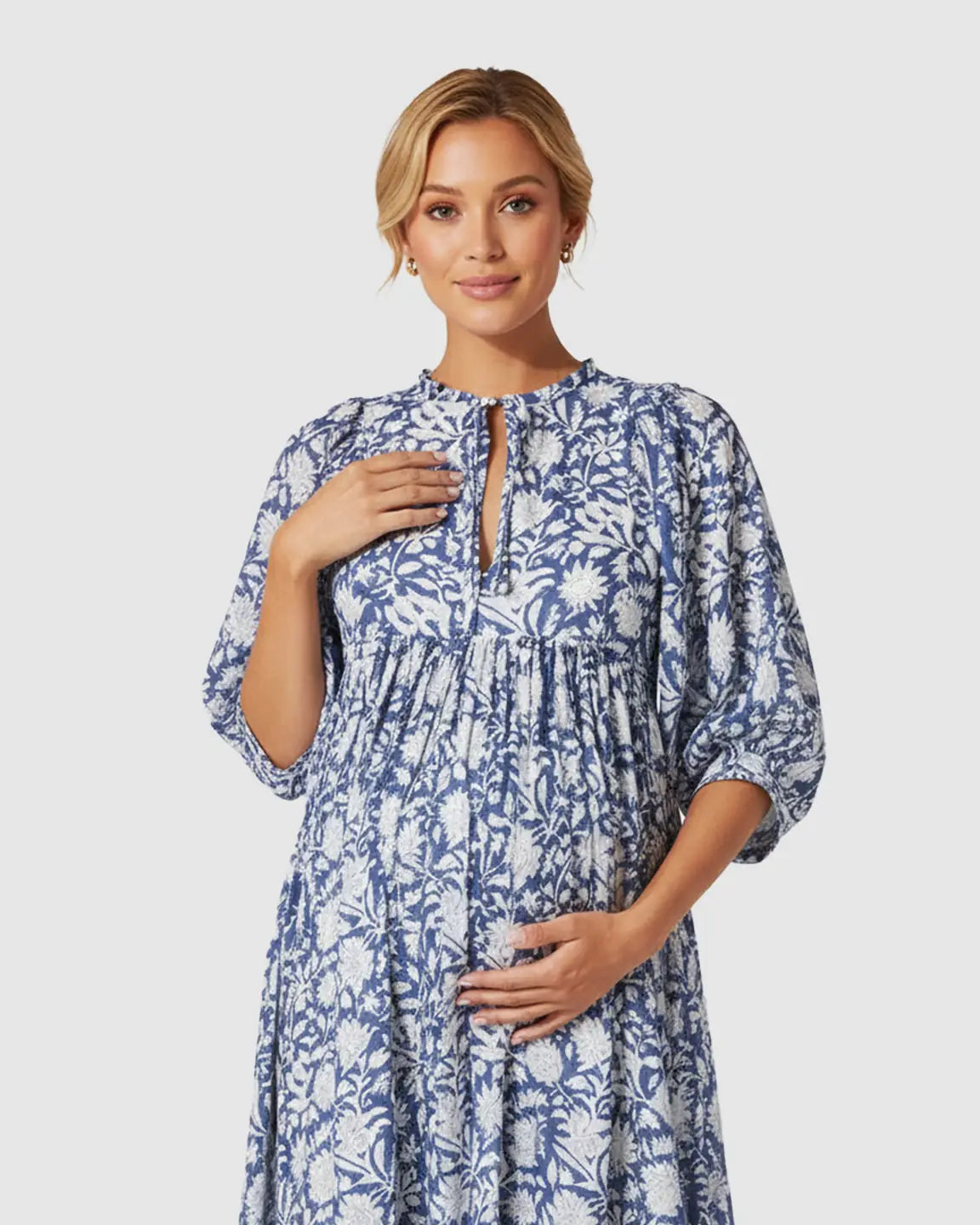 Maternity midi dress in blue and white floral print with gathered shoulders, puff sleeves, and knot detail.