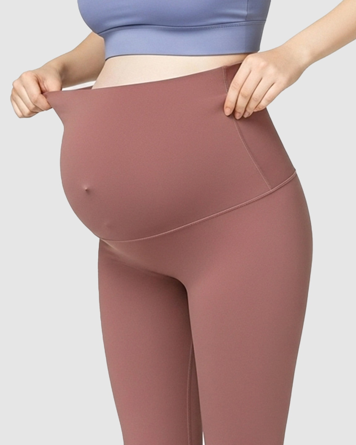 Pregnant woman wearing high-waisted, soft stretch maternity leggings in a dusty rose color, showing bump support.